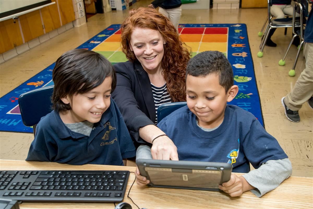 Teacher with two students looking at an iPad 